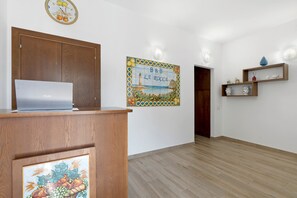 Ein Zimmer mit einem Holztisch, einem Laptop, einer Wanduhr, einer dekorativen Fliese und einer Holztür.