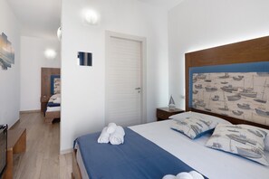 Ein Hotelzimmer mit Bett, Nachttisch, Holz-Kopfteil, einer Tür und einem kleinen Tisch mit Lampe.