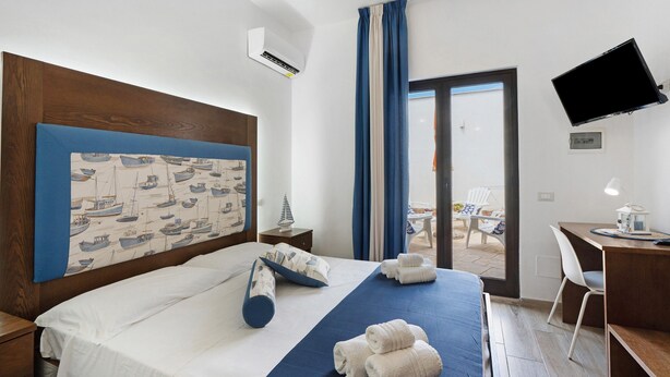 Une chambre d’hôtel avec un lit, un bureau, une télévision et une vue sur l’extérieur.