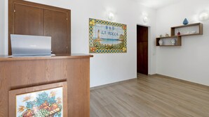 Une pièce avec un bureau en bois, un ordinateur portable, une horloge murale, un carreau décoratif et une porte en bois.
