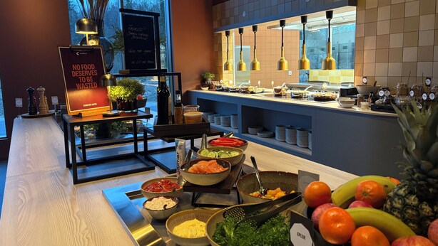 A buffet setup with various food items and a sign about food waste.
