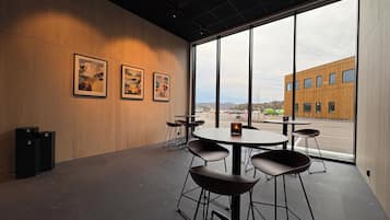 A modern interior with large windows, a wooden wall, and a view of a building outside.