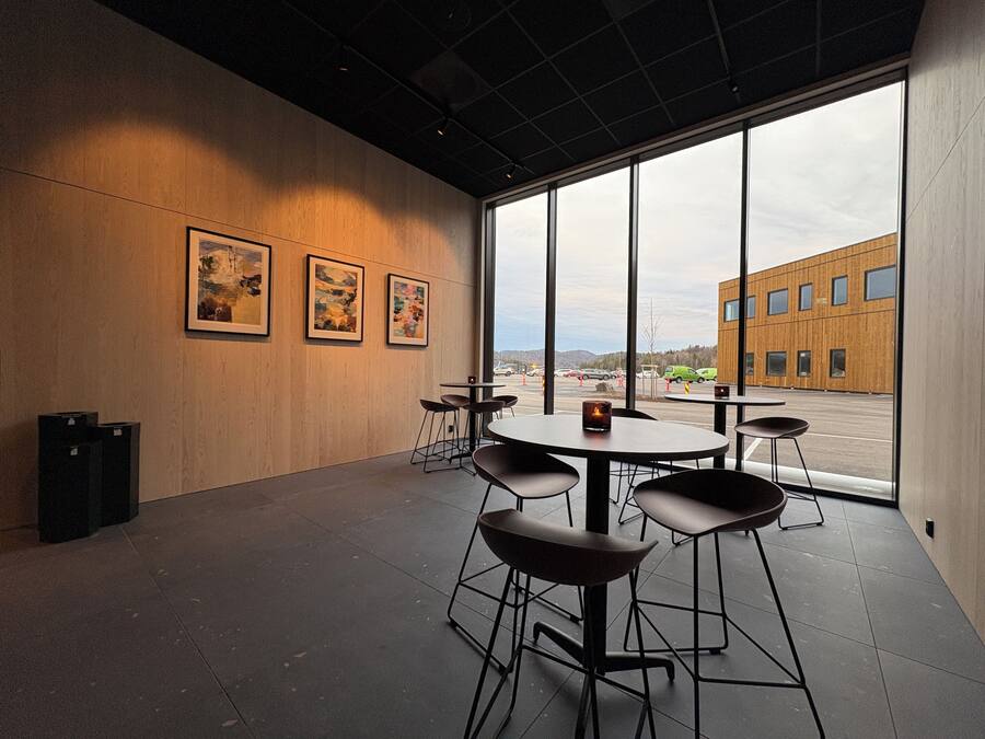 A modern interior with large windows, a wooden wall, and a view of a building outside.