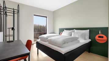 Un dormitorio moderno con cama, escritorio y ventana.