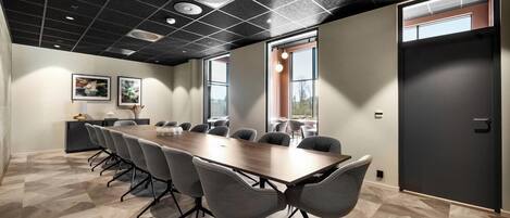 A conference room with a long table, chairs, a black ceiling, and large windows.