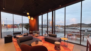 A modern interior with large windows, seating areas, and a view of a parking lot.