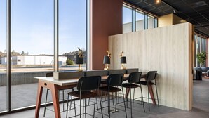 A modern bar area with a large window, a wooden partition, and black chairs.