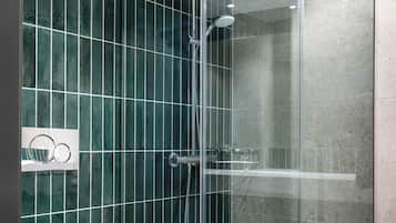 Un baño moderno con ducha envuelta en vidrio, inodoro blanco y pared con azulejos.