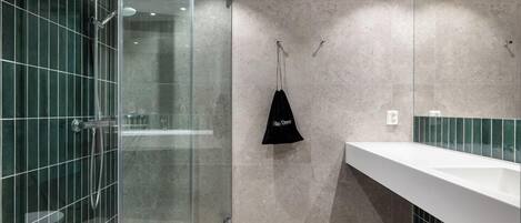Un baño moderno con ducha de vidrio, un lavabo blanco y una toalla colgada en un perchero.
