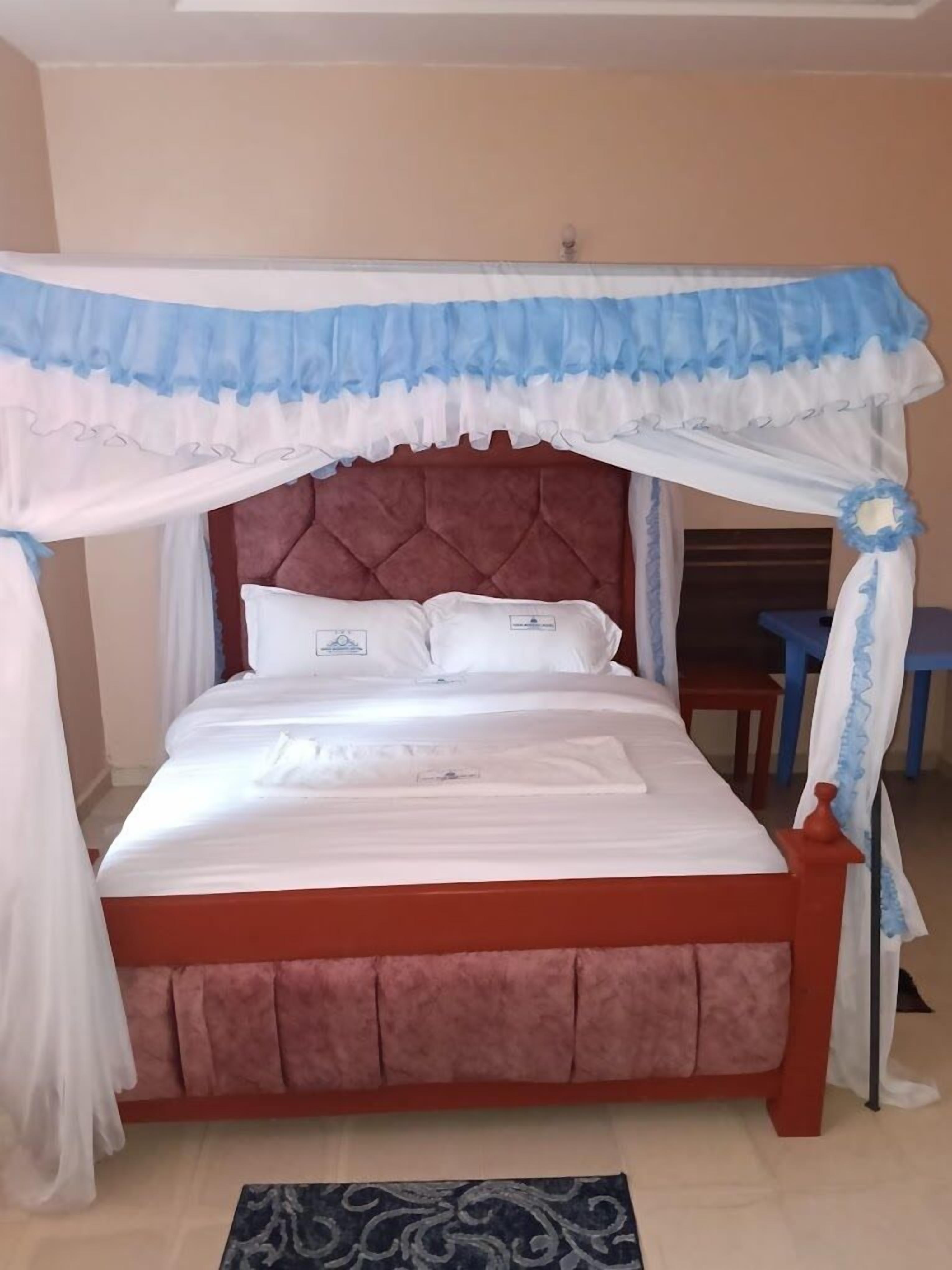 Una cama con dosel, cabecera y mesita de noche.