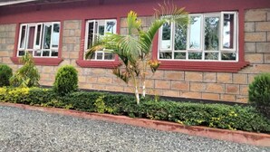 A building with a brick facade, red window frames, and a gravel driveway. - Good Morning Hotel Rongo (Rongo)
