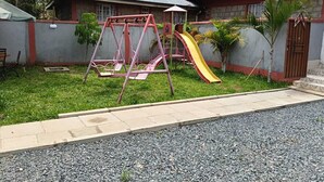 A playground with swings and a slide in front of a house with a metal roof. - Good Morning Hotel Rongo (Rongo)