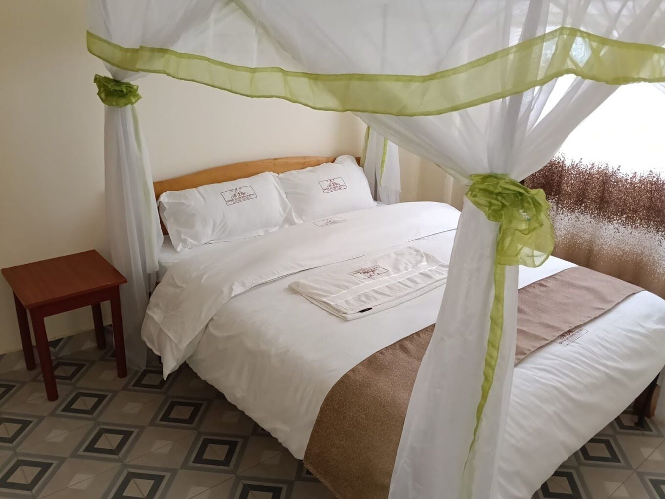 A bed with a canopy, white bedding, and a small bedside table.