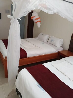 A hotel room with two beds, a wooden headboard, and a canopy bed.