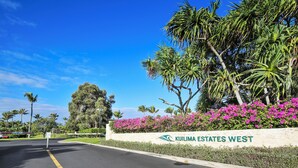Una carretera que conduce a una entrada con puerta de acceso y un cartel que dice 'Kuilima Estates West'.