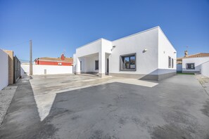 Un bâtiment moderne à deux étages, doté d’un toit plat, d’un patio couvert et d’une entrée bien visible.