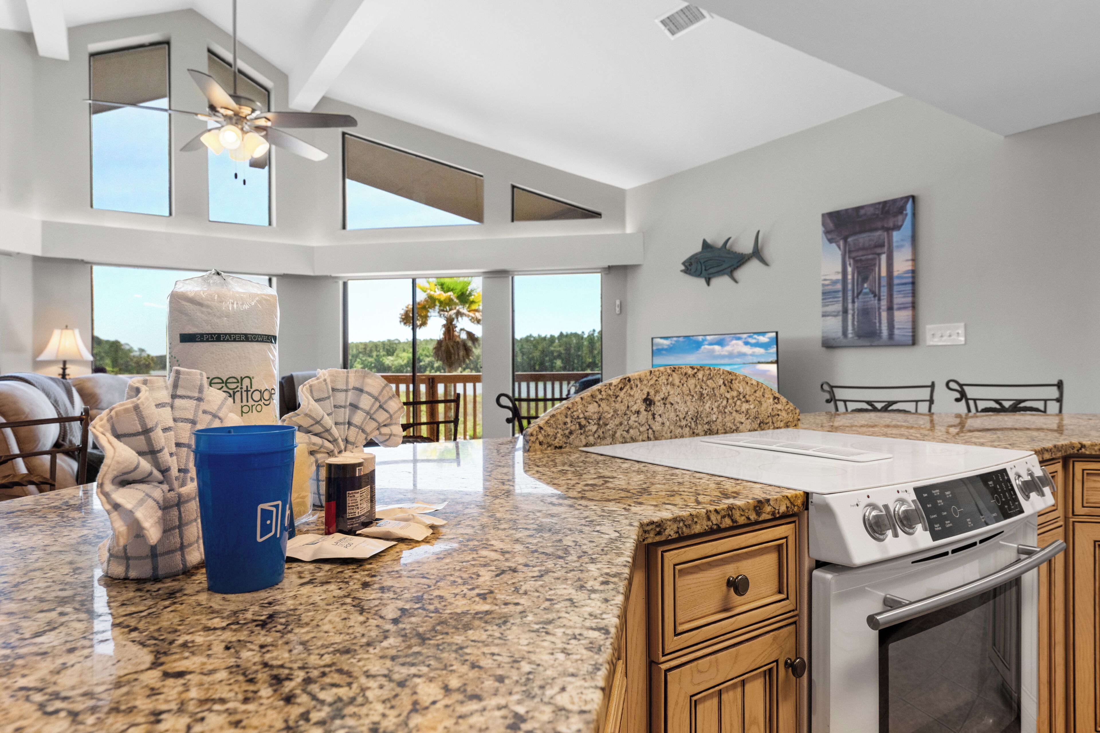A modern kitchen with granite countertops, a built-in oven, and a large window overlooking a deck.