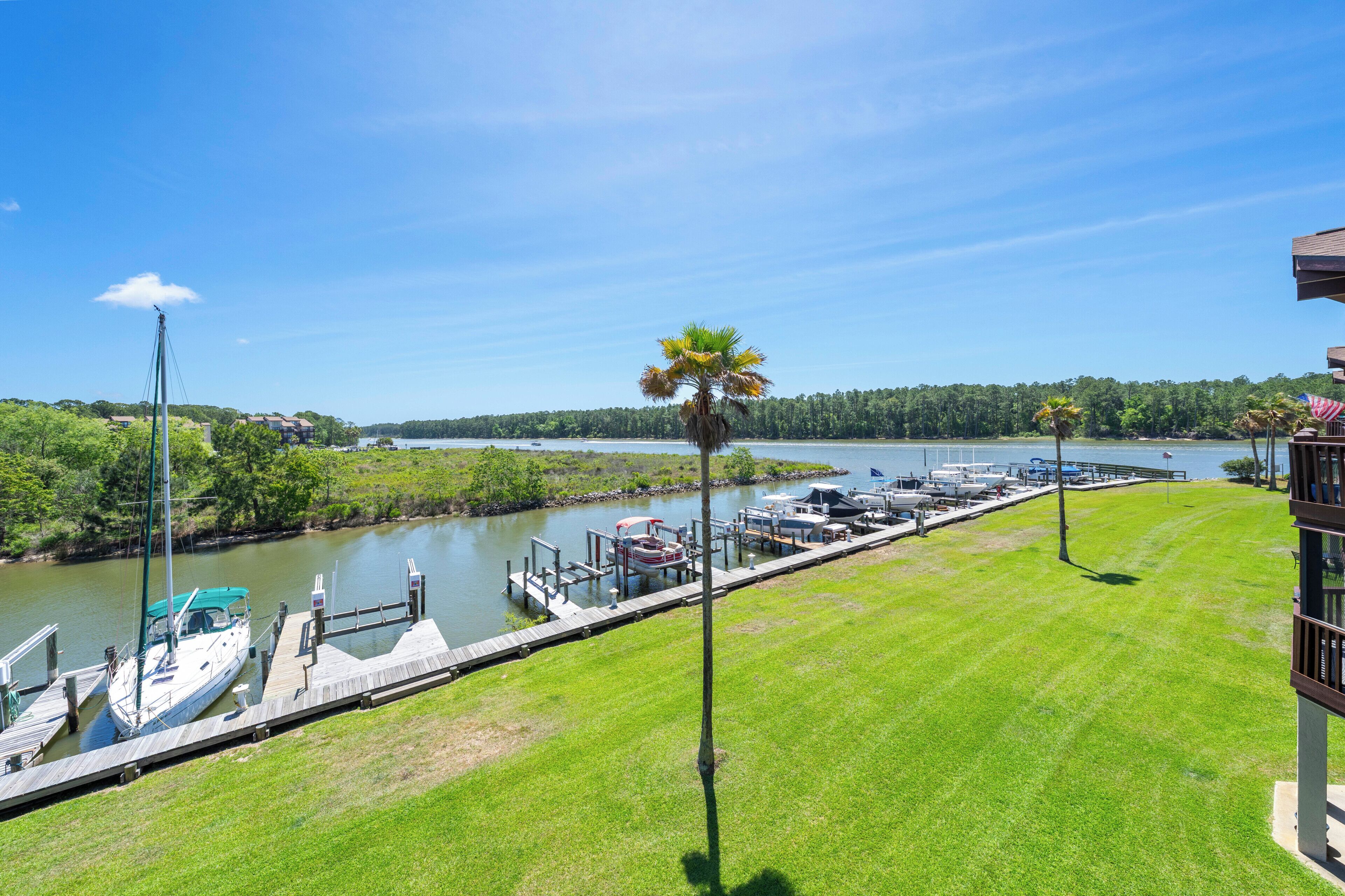 A marina with boats docked, a grassy area, and a clear view of the water.