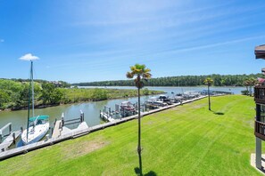 A marina with boats docked, a grassy area, and a clear view of the water. - Sailboat 201 with Pool (Gulf Shores)