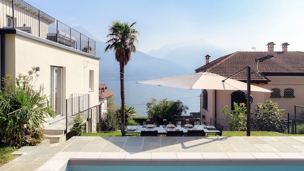 Ein Poolbereich mit Essbereich mit Blick auf ein Gewässer und Berge.