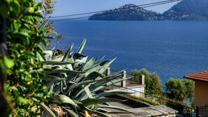 Eine Küstenansicht mit einem Berg im Hintergrund, einer Brücke und einem Gebäude mit rotem Dach.