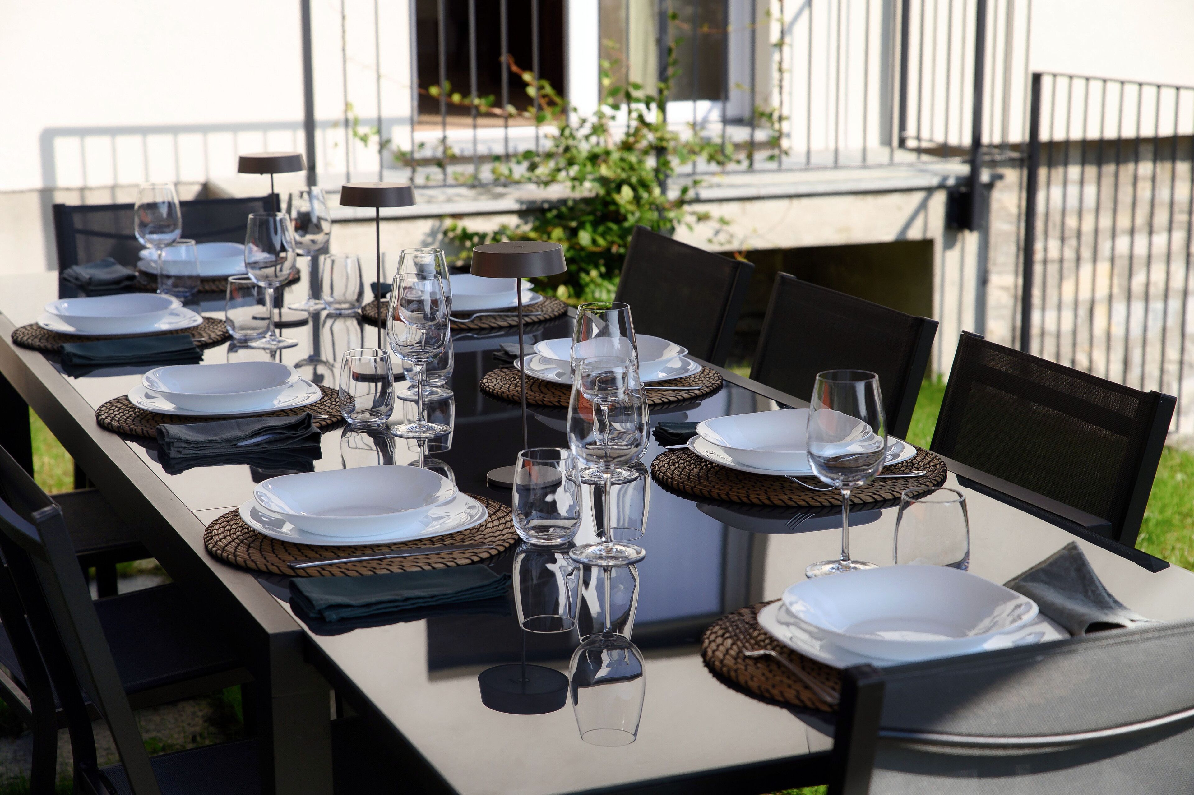 Une table à manger dressée avec des assiettes, des verres et des couverts, entourée de chaises.