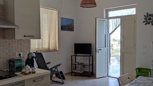 A kitchen with a TV, coffee maker, and a dining area with a table and chairs. - Apartment with terrace a few steps from the sea (San Lorenzo)