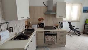 A compact kitchen with a sink, stove, and a small dining area. - Apartment with terrace a few steps from the sea (San Lorenzo)