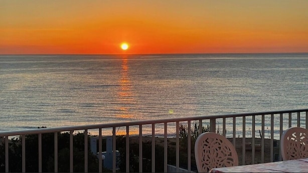 A sunset view from a balcony with a railing and chairs, overlooking the sea. - Apartment with terrace a few steps from the sea (San Lorenzo)