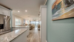 A modern kitchen with a central island, white cabinetry, and stainless steel appliances. - Sand Pointe 137: Luxury Beachfront Escape with Stunning Gulf Views! (Sanibel)