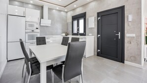 A modern kitchen with white cabinets, a dining table, and black chairs.