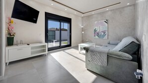 A modern living room with a sofa, a TV, a coffee table, and a large window.