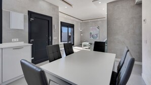 A modern meeting room with a large table, black chairs, a white cabinet, and a black door.