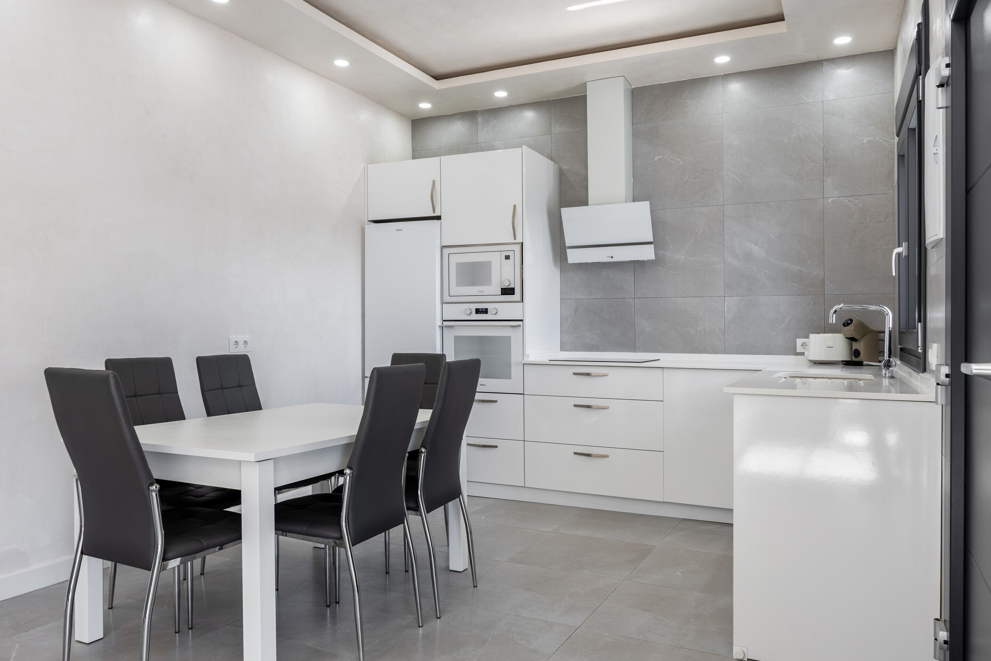 A modern kitchen with white cabinets, a built-in microwave, and a sink.