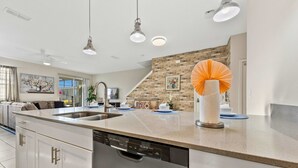Une cuisine moderne équipée d’un lave-vaisselle, d’un évier et agrémentée d’un éventail décoratif en papier orange.