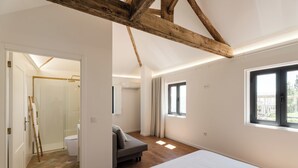 Een slaapkamer met een bed, een raam en een houten plafondbalk.