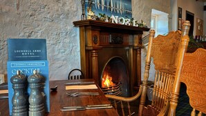 A wooden dining table with a fireplace, a sign for Lochnell Arms Hotel, and a cocktail menu.