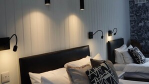 A hotel room with a large bed, two bedside tables, and a wall-mounted light fixture.