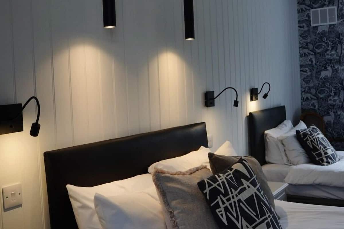 Ett hotellrum med en stor säng, två sängbord och en väggmonterad lampa.