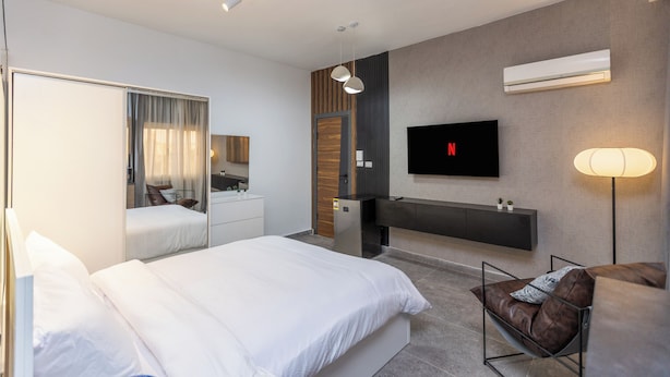 Una habitación de hotel moderna con una cama grande, un escritorio, un televisor y una zona de estar.