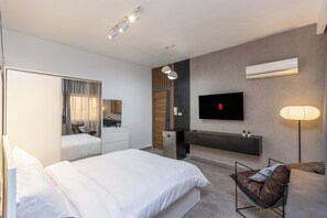 Une chambre d’hôtel moderne équipée d’un grand lit, d’un bureau, d’une télévision et d’un coin salon.