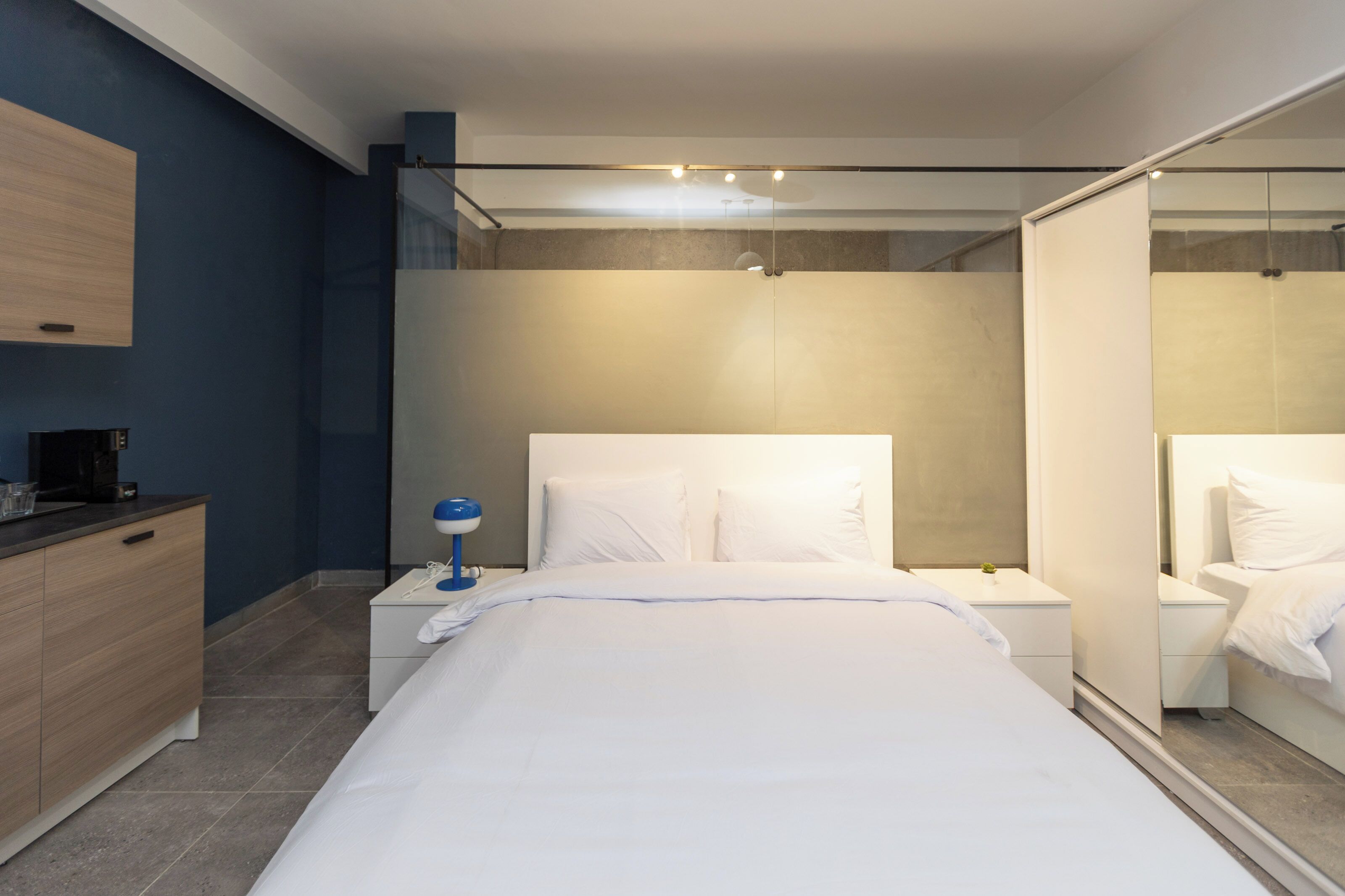 Un dormitorio moderno con una cama grande, mesitas de noche, un velador, un espejo y un armario.