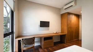 Ein modernes Schlafzimmer mit einem Holztisch, einem Stuhl, einem Kleiderschrank und einem Wand-Fernseher.