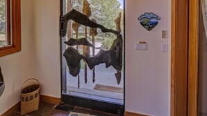 A door with a rustic metal sculpture, a welcome sign, and a basket by the entrance. - Vail Hideaway - Forest Views, Deck & Comfort (Vail)