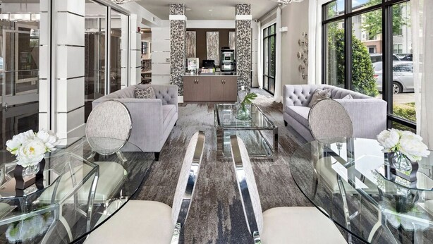 A modern living room with a glass coffee table, two sofas, and a kitchen area with a refrigerator and microwave. -  Landing Furnished Apartments - Charlotte Northlake (Charlotte)