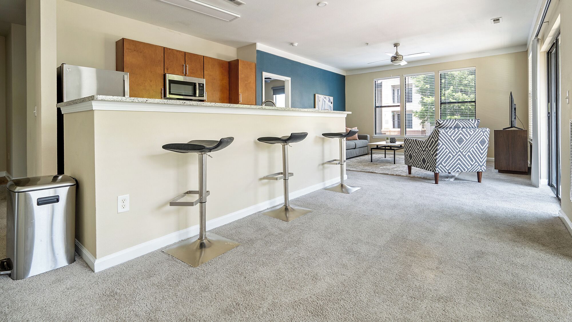 Une cuisine moderne avec un coin bar, des appareils en acier inoxydable et une vue sur le salon.