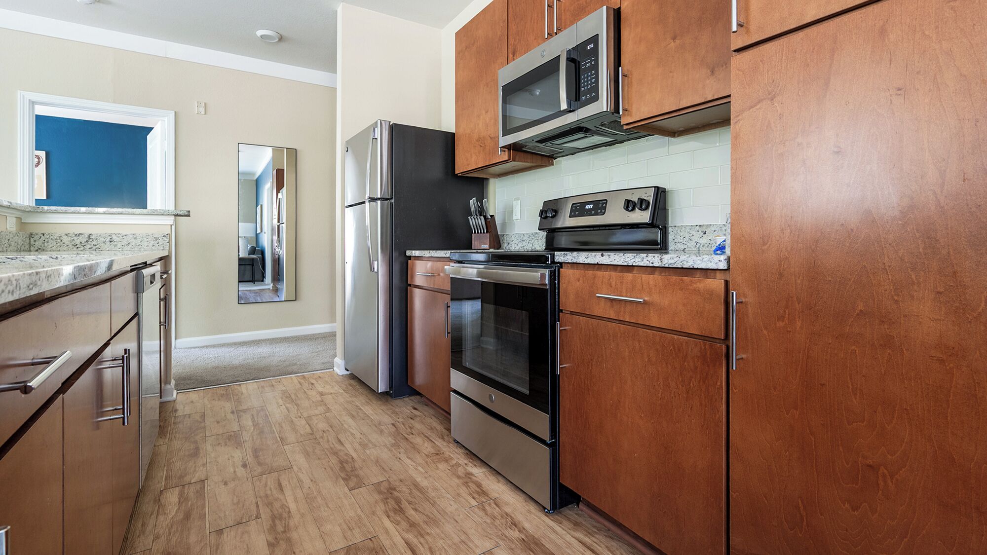 A modern kitchen with stainless steel appliances, wooden cabinets, and a granite countertop.