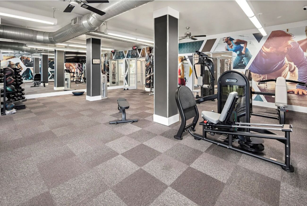 Una palestra con attrezzature per esercizi, specchi e una reception.