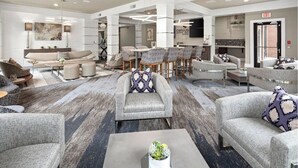 A spacious lobby with a modern design, featuring sofas, armchairs, and a coffee table with a plant centerpiece. -  Landing Furnished Apartments - Charlotte Northlake (Charlotte)