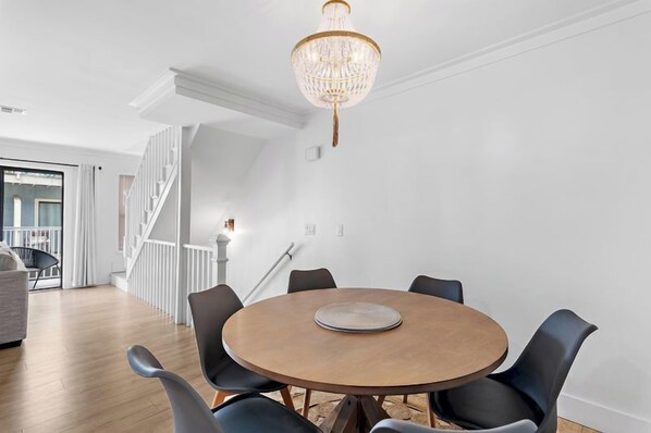 Een eetgedeelte met een ronde tafel, stoelen en een kroonluchter.
